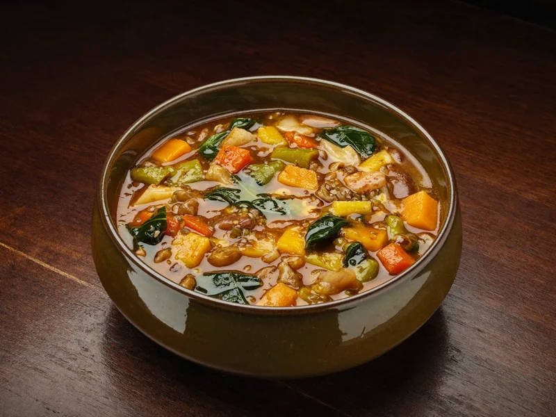 Ciotola di minestrone morbido di verdure e legumi con olio d'oliva