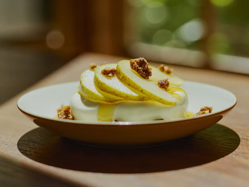 Ricotta cremosa con pere a fette e noci tritate in un piattino